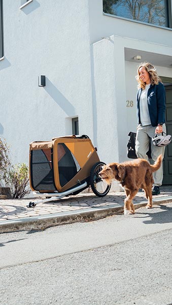 Woman with dog and Croozer dog bike trailer in sundown yellow - safe transport for medium-sized dogs