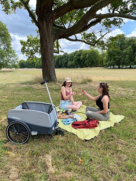 Two friends enjoying park picnic with Croozer cargo trailer - cycling to outdoor destinations