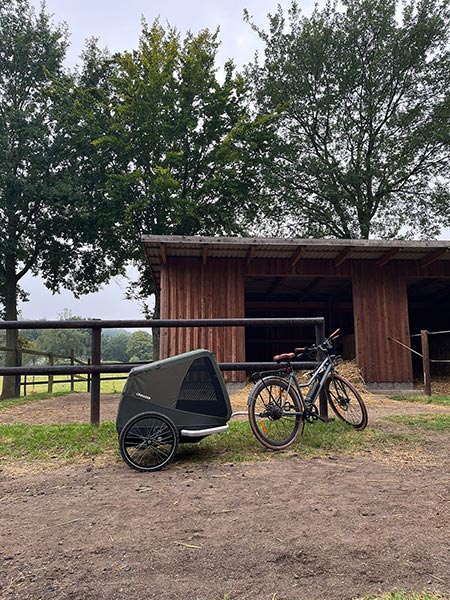 Croozer dog trailer parked at wooden barn - rural cycling and farm transport solution