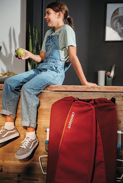 Young smiling girl with folded Croozer cargo bike trailer in modern kitchen