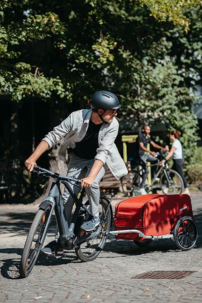 Man riding his bike in the sunny city with Croozer Cargo attached