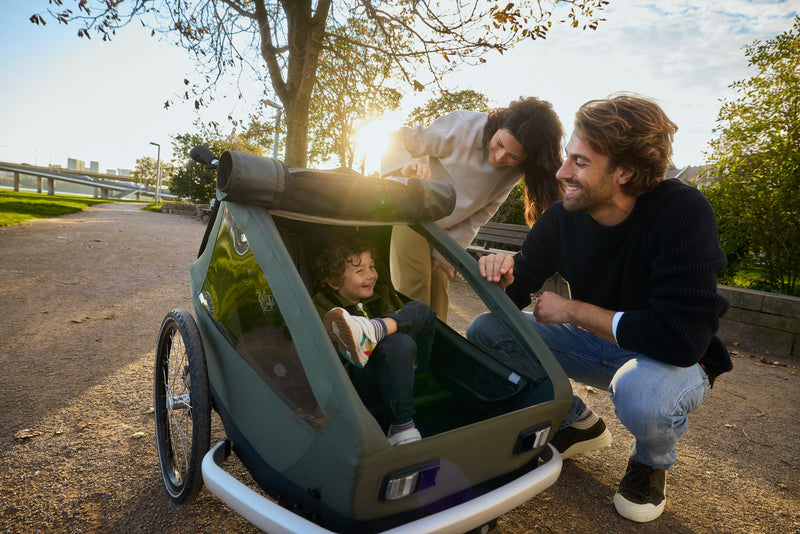 Familie bei einem sonnigen Ausflug, glückliches Kind im Croozer Kid Keeke