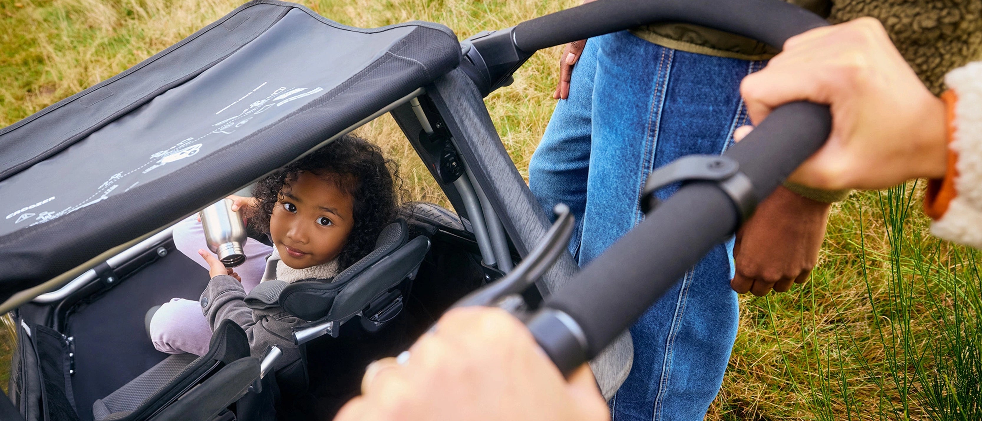 Parent using Croozer Yuuna in buggy mode as child gazes at parent through back opening
