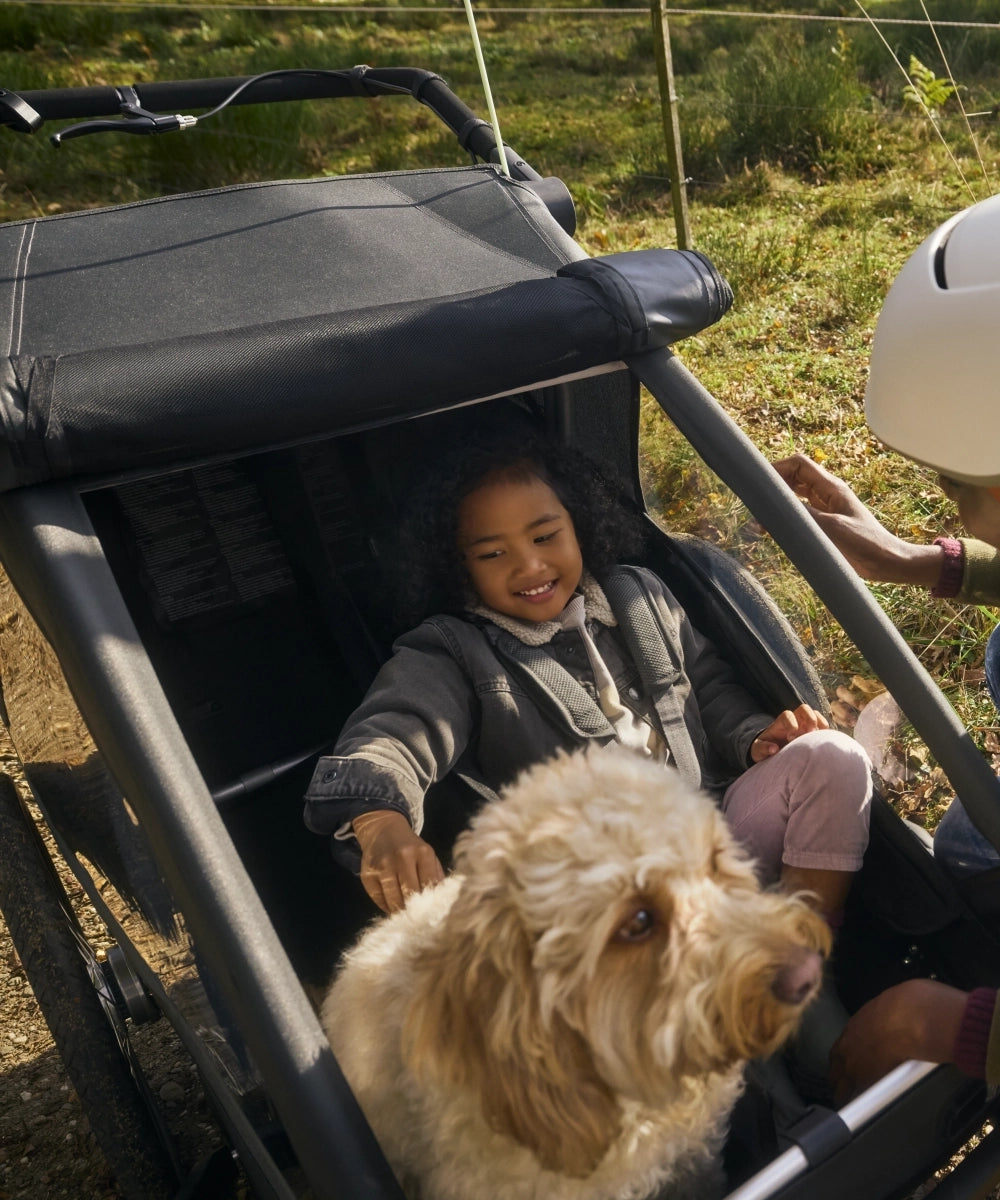 Mutter, Tochter und Hund gemeinsam unterwegs mit modularem Fahrradanhänger Croozer Yuuna