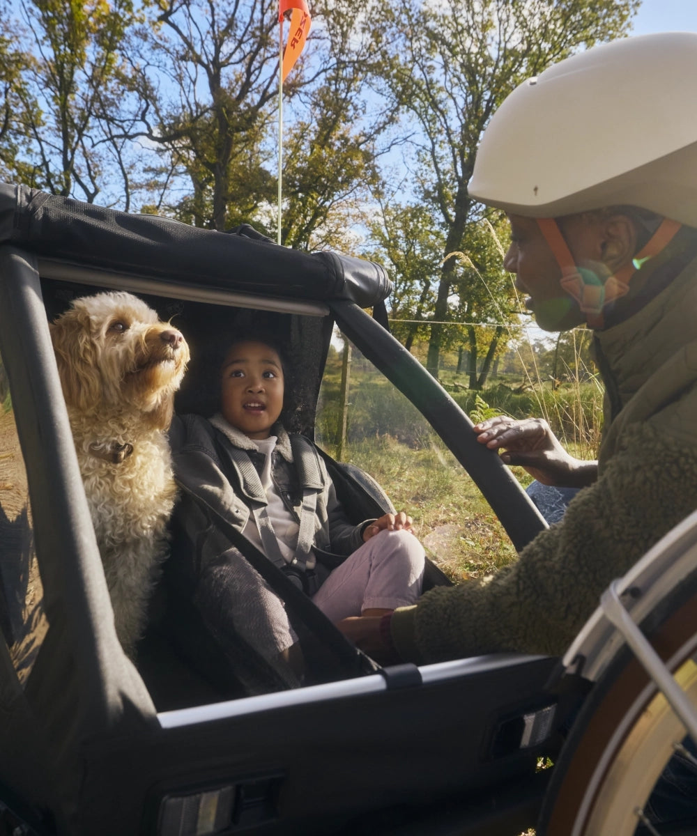 Kind und Hund gespannt auf Fahrt mit modularem Anhänger Croozer Yuuna