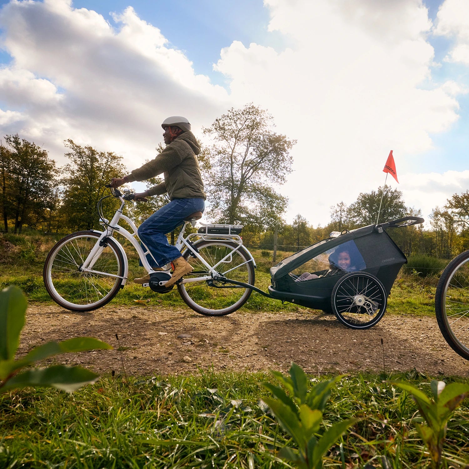 Fahrrad fahrende Mutter unterwegs mit Kind und Hund im modularen Croozer Yuuna