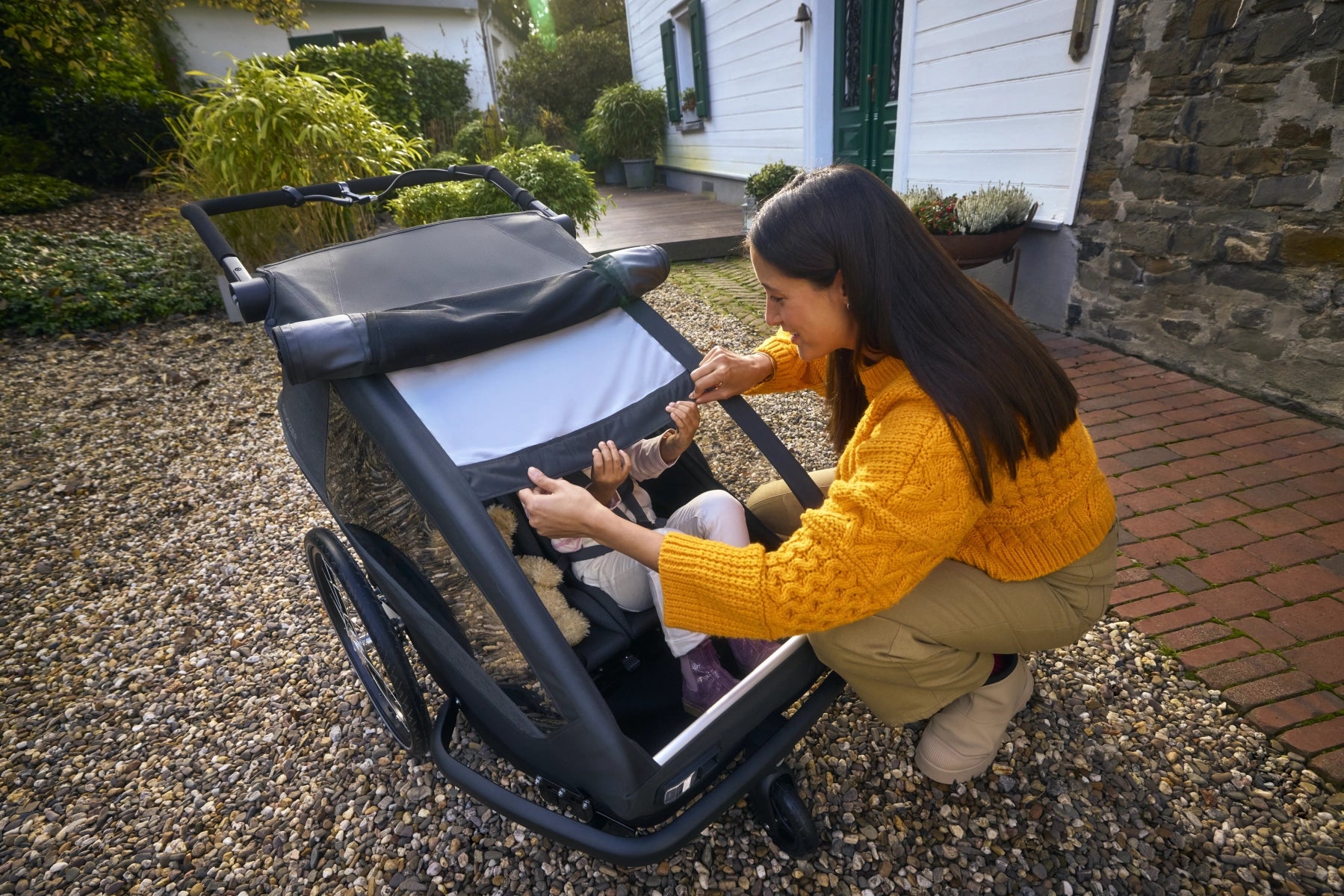 Mutter schützt Kind im Croozer Yuuna mit integriertem Sonnenschutz