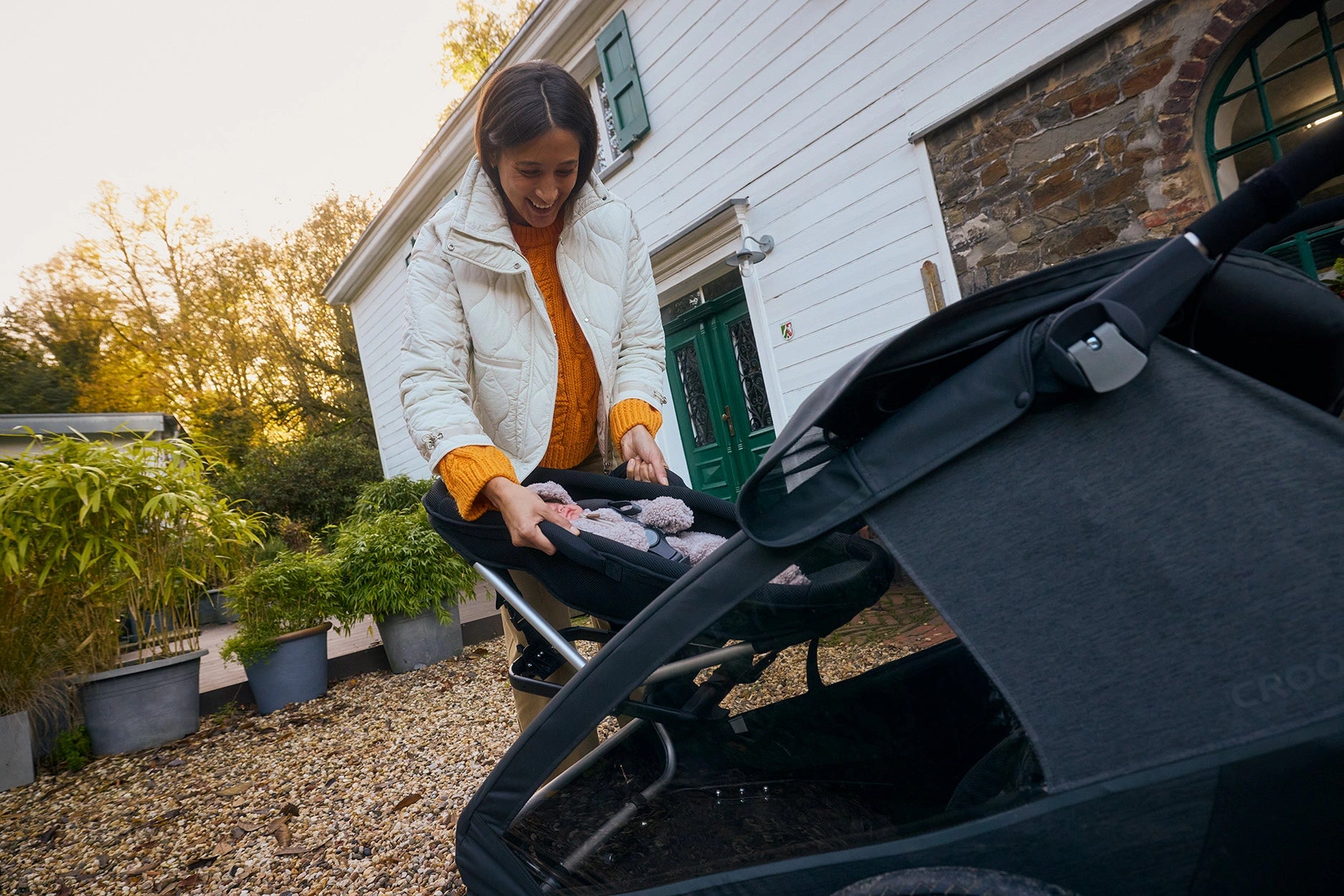 Woman securing baby in Yuuna baby module within Yuuna trailer