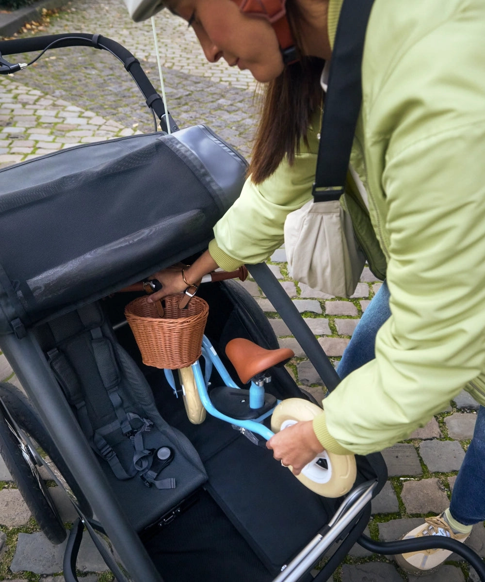 Frau belädt Croozer Yuuna mit Kinderfahrrad neben Premium Sitz