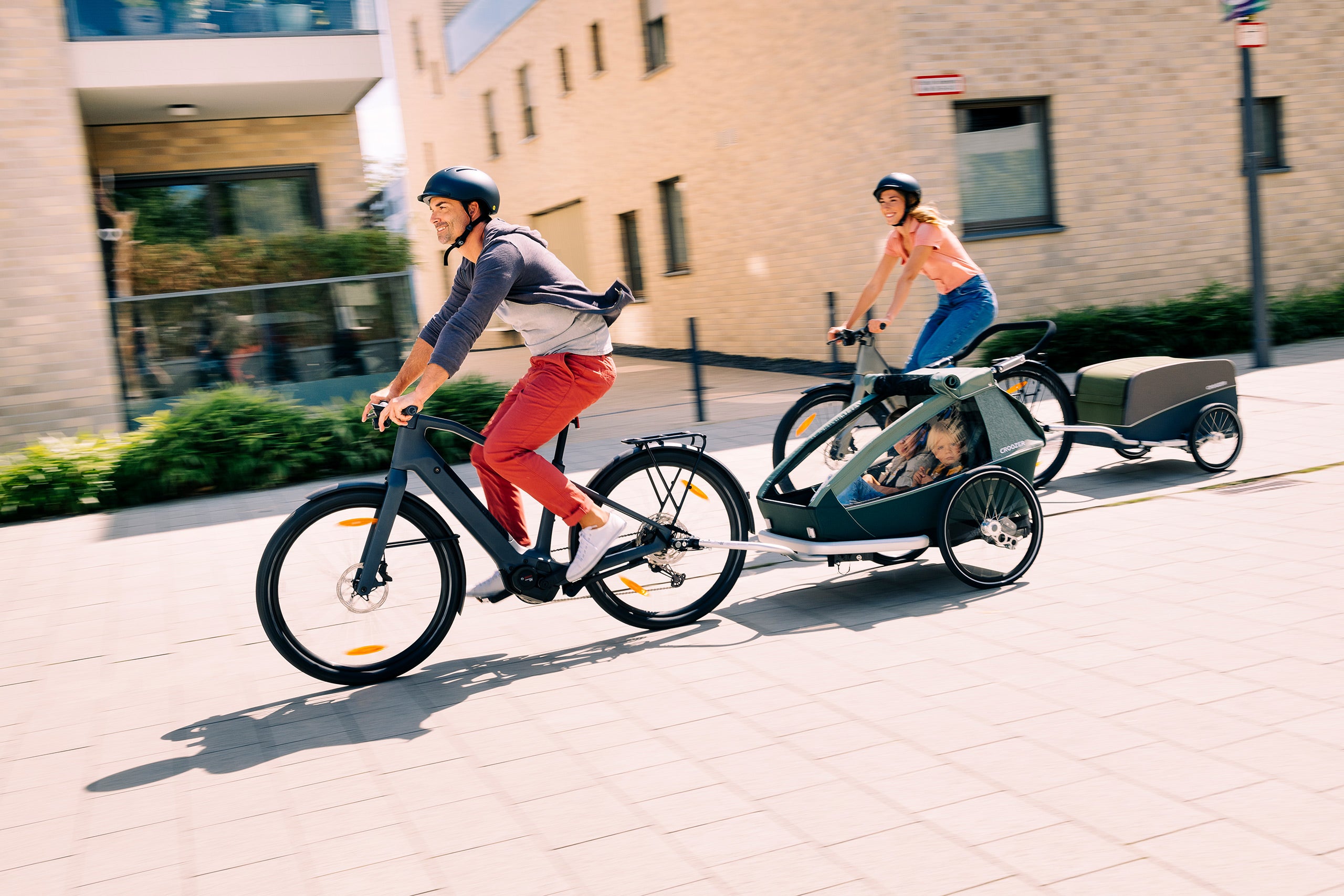 Happy family on bike tour with their two kids in Croozer Kid bike trailer