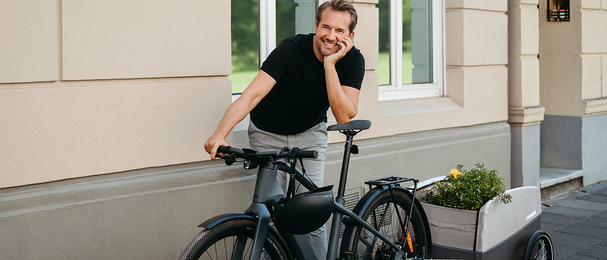 Happy man with e-bike and Croozer cargo trailer - urban cycling and sustainable transport solution