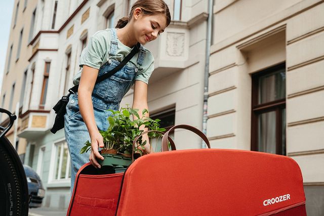 Young woman packing her Croozer Cargo bike trailer with plants