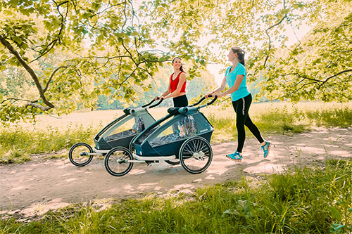 Two women jogging with their Croozer Kid trailer and installed jogger wheel