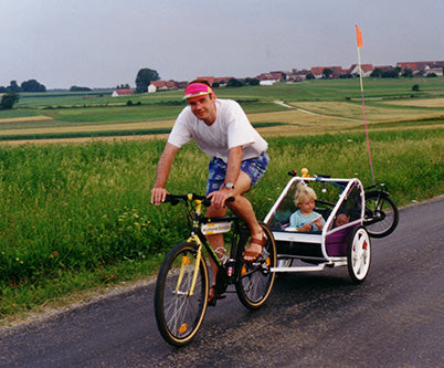 Andreas Gehlen cycling with his daughter in the bike trailer with attached safety flag