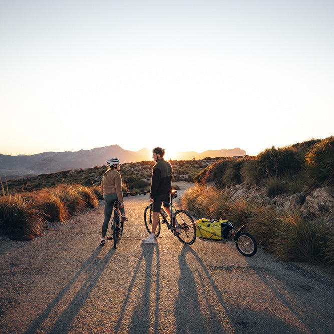 Couple on bike tour with BOB Ibex cargo trailer and BOB bag - taking a break in sunset