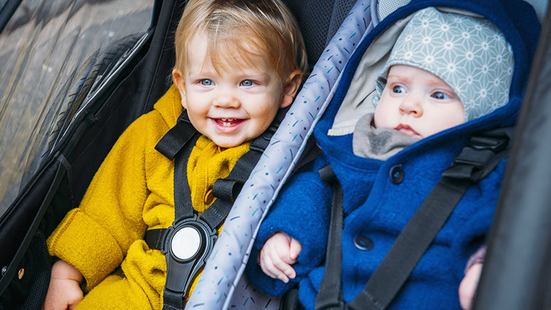 Happy child and baby next to each other in Croozer Kid two-seater bike trailer