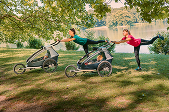 Laufmamalauf cooperation with Croozer - two women performing fitness exercises with Croozer trailers