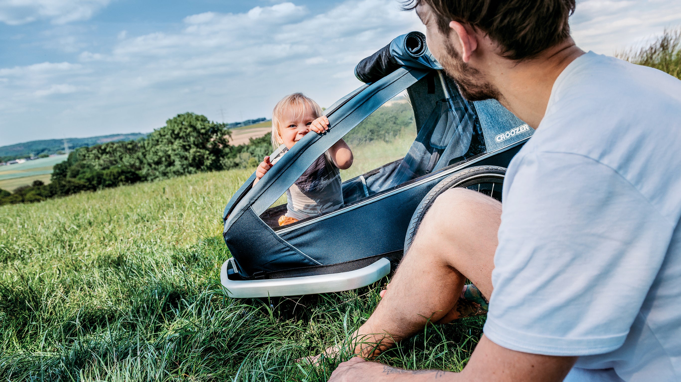 Father and baby daughter enjoying their time outside - Croozer kid bike trailer with them