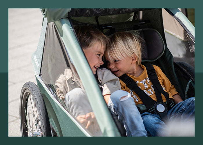 Two happy little kid brothers enjoying their time in Croozer Kid bike trailer
