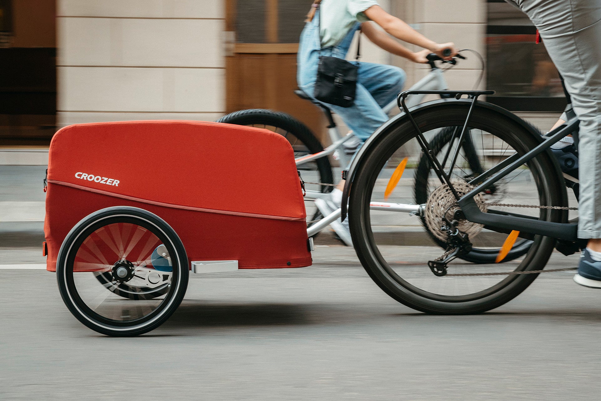 Croozer cargo bike trailer in red cycling through urban street - sustainable city transport solution
