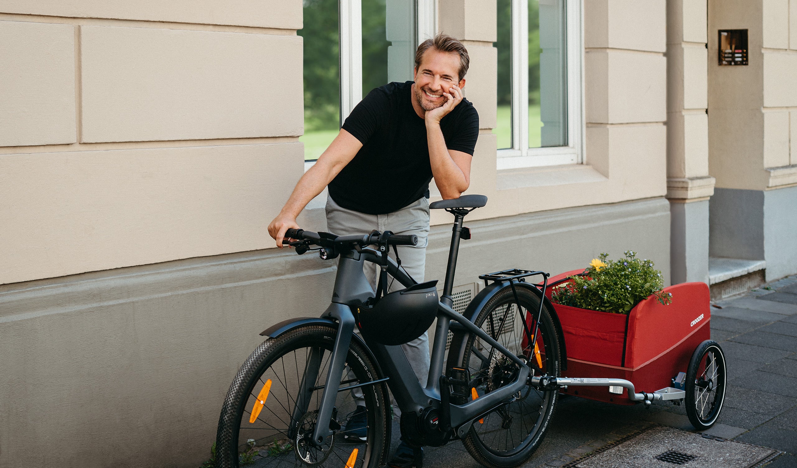 Happy man with loaded Croozer Cargo bike trailer in the city