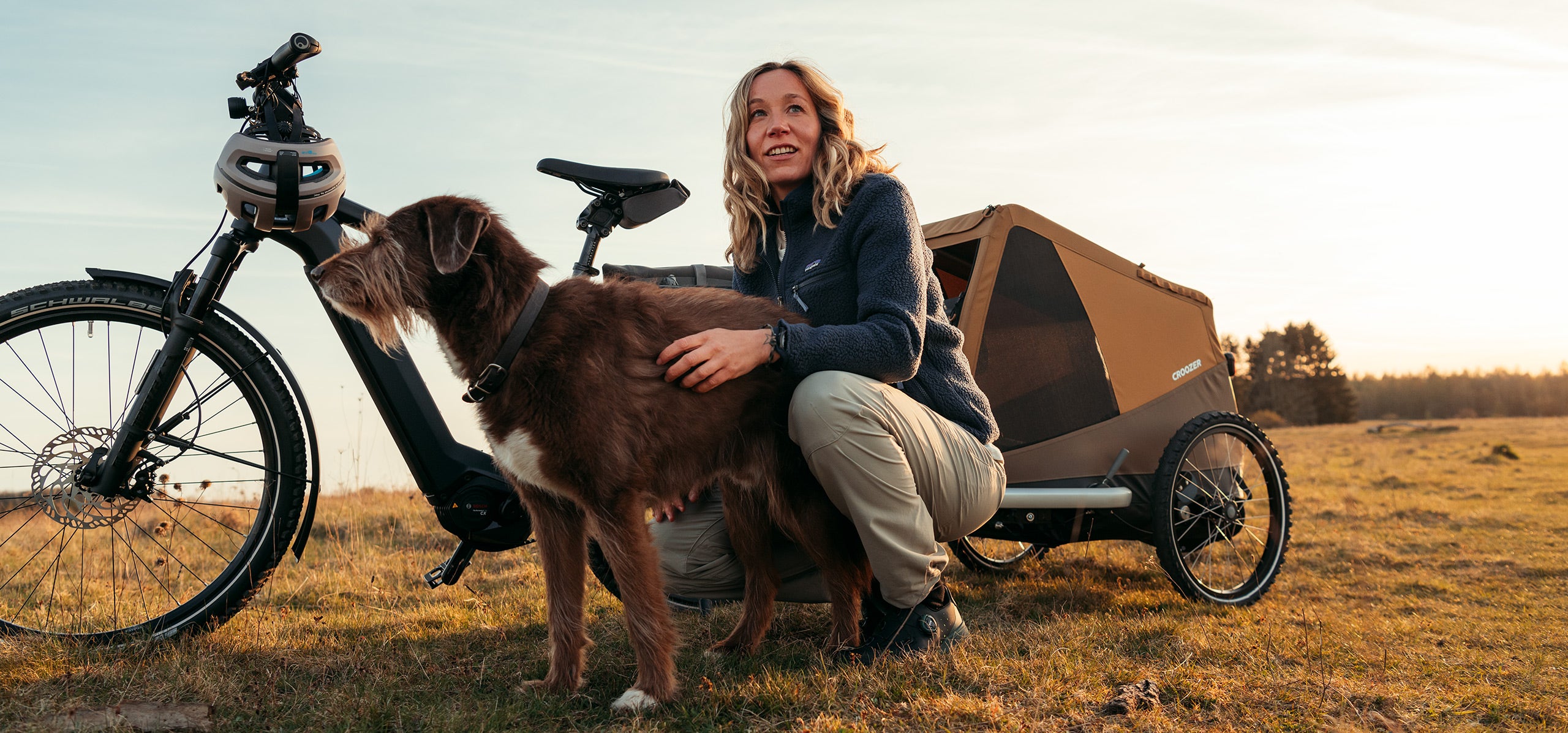 Woman petting her dog while taking a break from countryside bike tour - Croozer Dog trailer with them