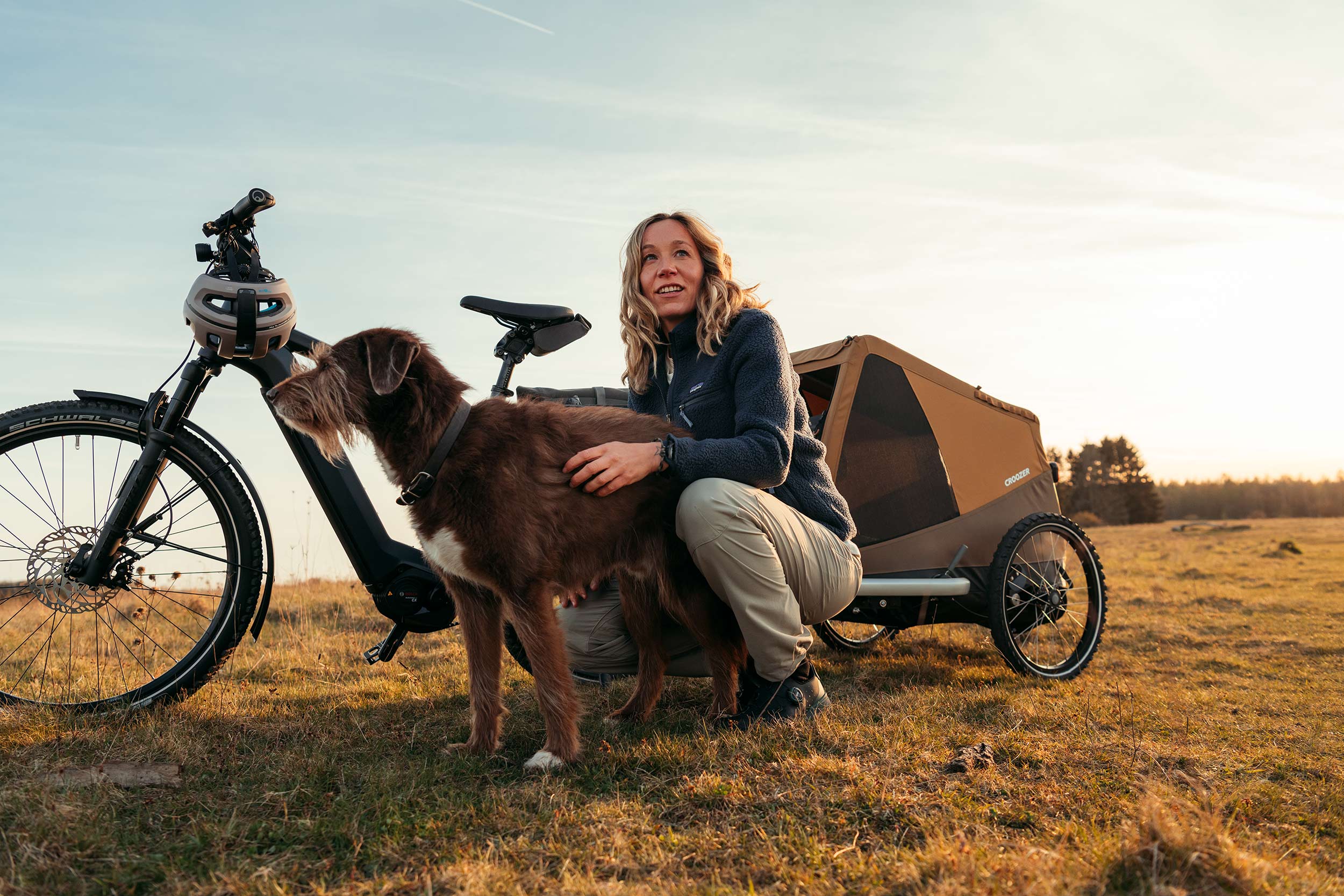 Woman petting her dog while taking a break from countryside bike tour - Croozer Dog trailer with them