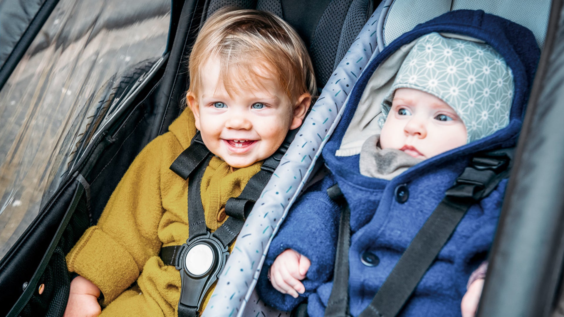 Two happy children sitting in Croozer Kid bike trailer