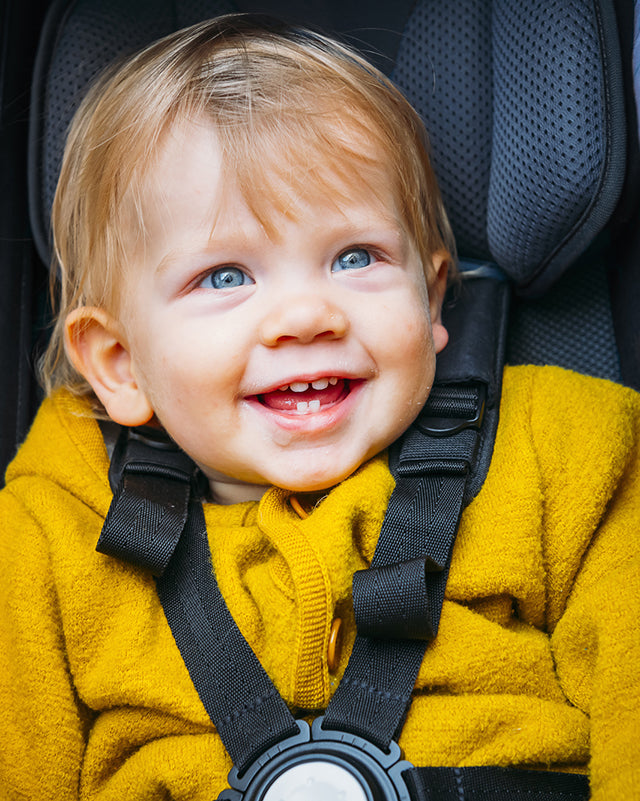 Happy smiling baby sitting in Croozer baby seat with 5-point safety belt