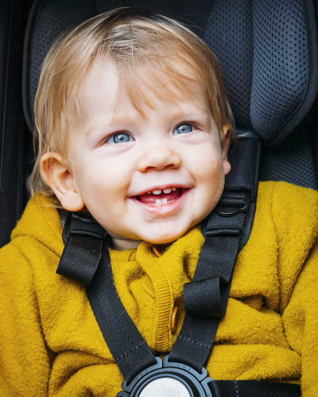 Happy smiling baby sitting in Croozer baby seat with 5-point safety belt