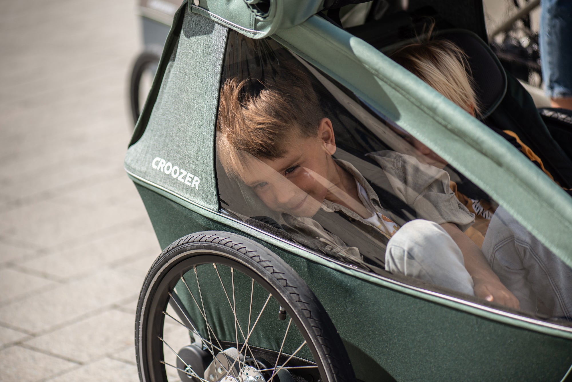 Happy smiling boy enjoying view from Croozer Kid bike trailer