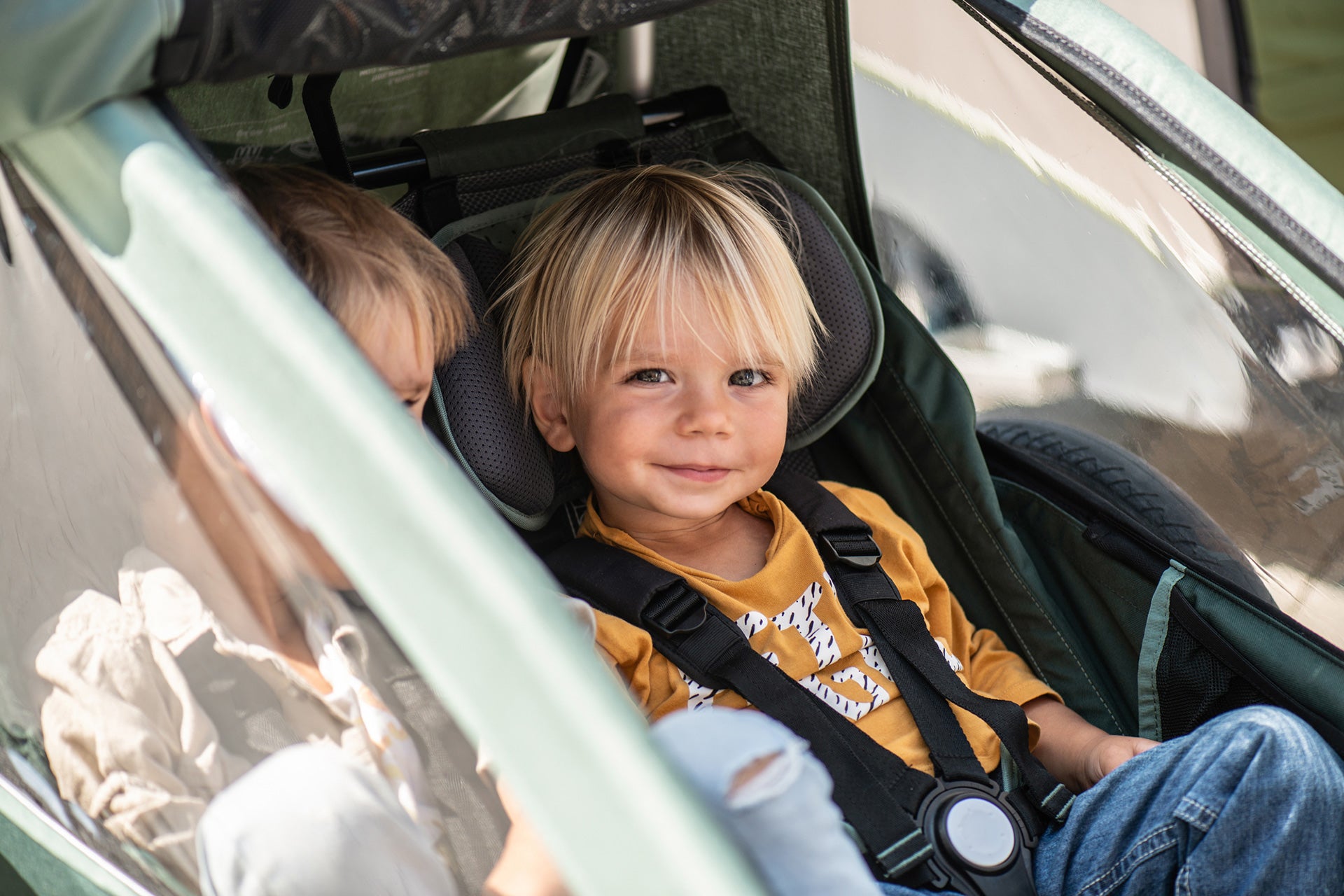 Two happy siblings sitting next to each other in Croozer Kid bike trailer