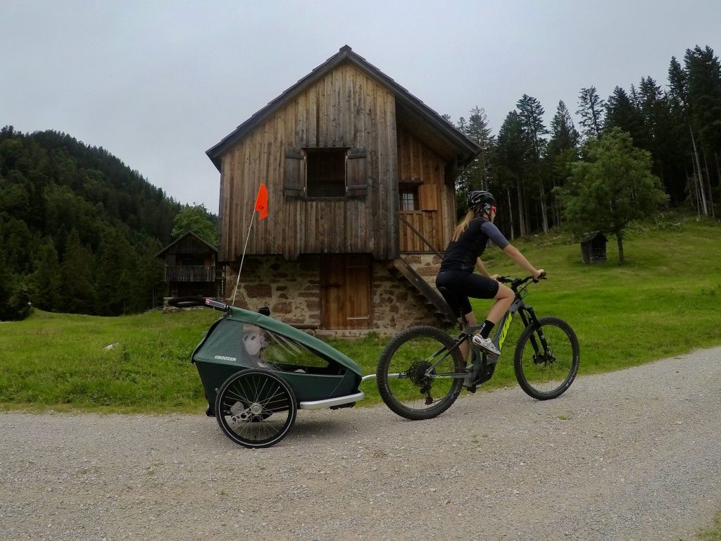 Mother and child on tour with bike and Croozer Kid trailer with safety flag - riding through rural areas