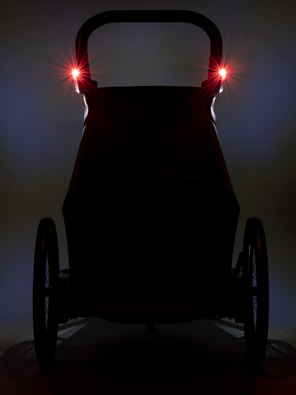 Rear view of Croozer Kid Vaaya trailer in dark setting with red sensor light illuminated