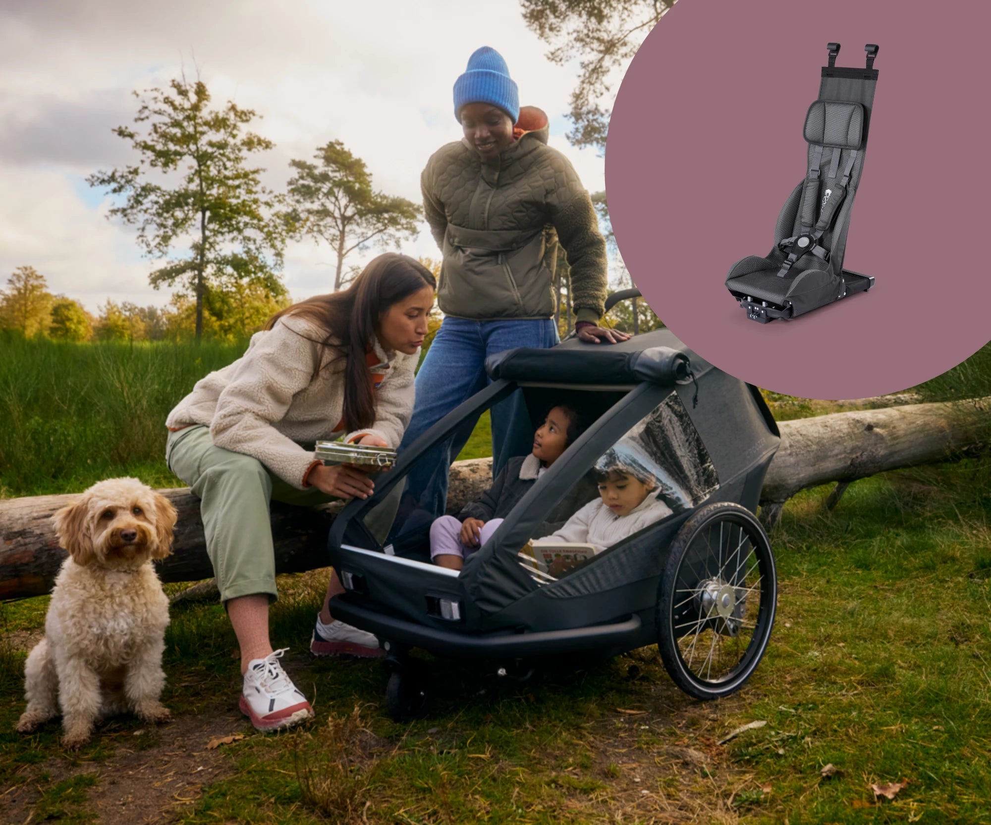 Family with Croozer Yuuna bike trailer containing two children sitting in the basic seat module in park setting with dog and product picture on the top right