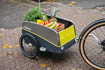 Croozer cargo bike trailer carrying fresh vegetables and groceries attached to bicycle wheel